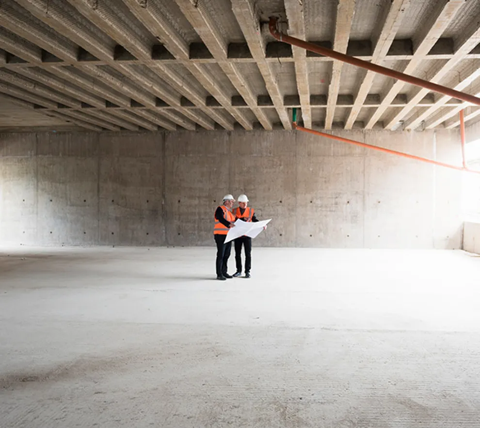 to arbeidere i et stort lokale i betong