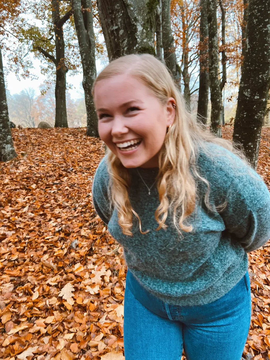 Foto av Sigrid som ler i høstlige omgivelser