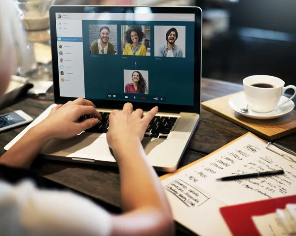 Nærbilde av kvinnehender som skriver på laptop mens hun er i Skype videomøte