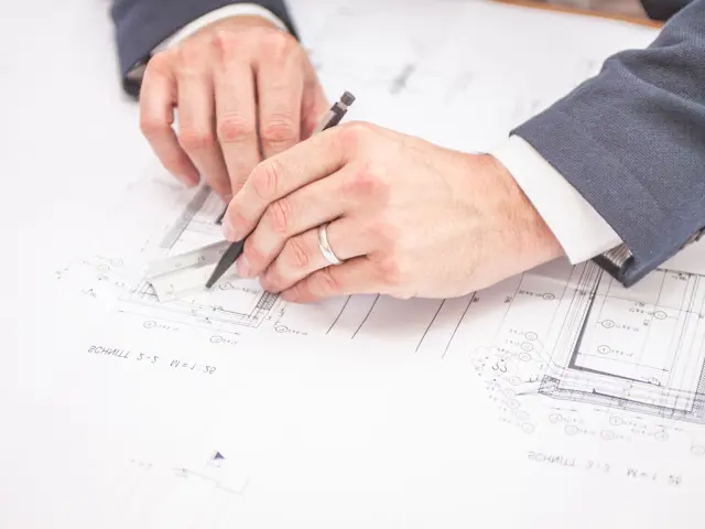 Nærbilde av hender i dress som tegner en teknisk tegning