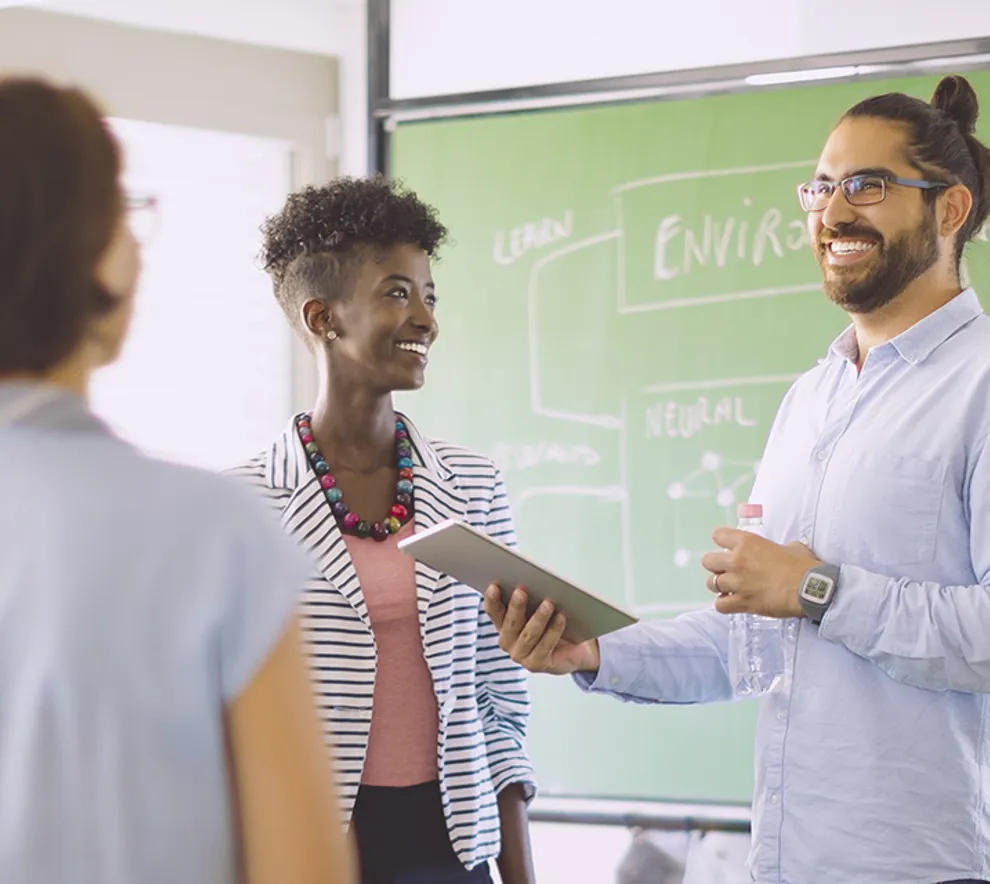 Smilende kollegaer samlet stående i kontorlokale for teamarbeid