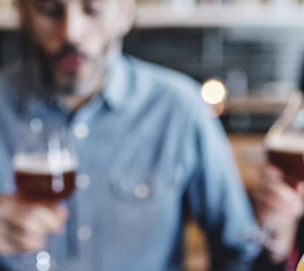 To kvinner og en mann lukter på innhold i ølglass.