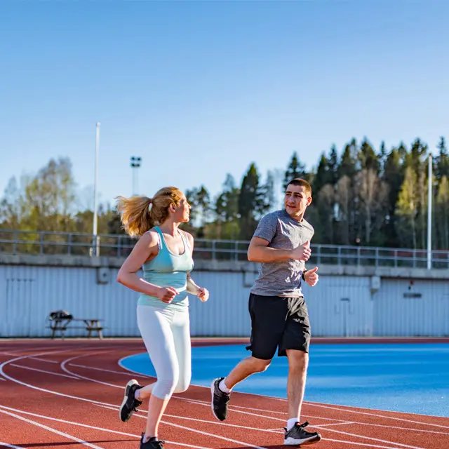 En kvinne og en mann jogger på løpebane