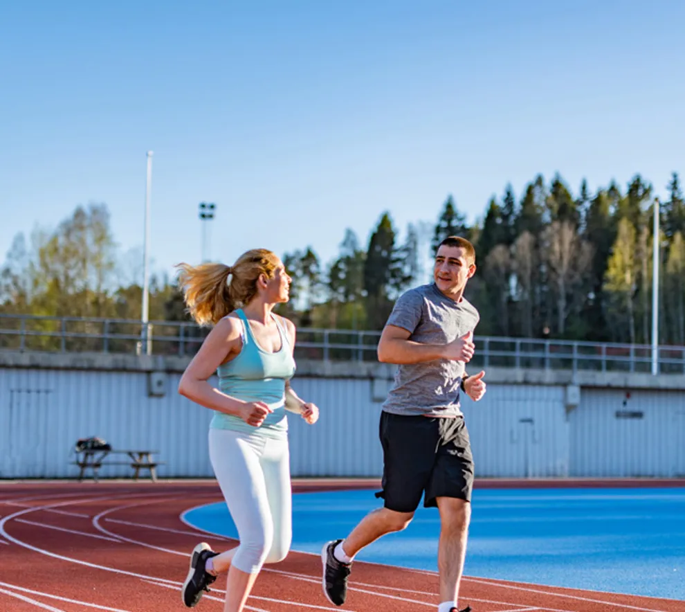 En kvinne og en mann jogger på løpebane