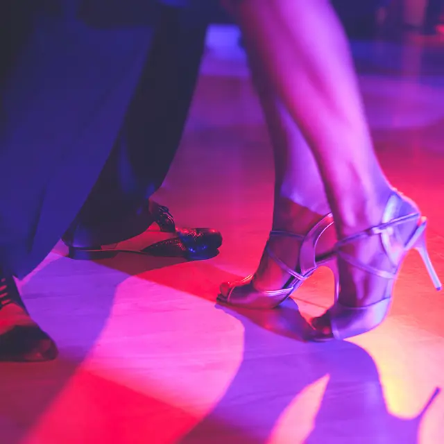 Nærbilde av beinene til par som danser, pensko og høyhælte sko