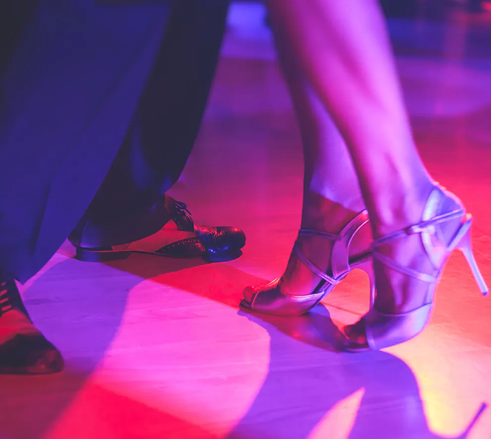 Nærbilde av beinene til par som danser, pensko og høyhælte sko