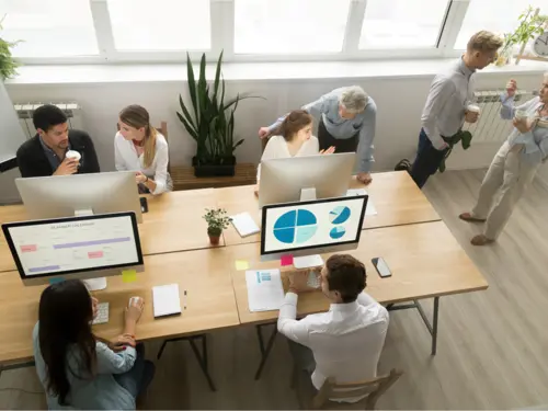 Illustrasjonsbilde av et kontor med flere datamaskiner og både unge og eldre ansatte