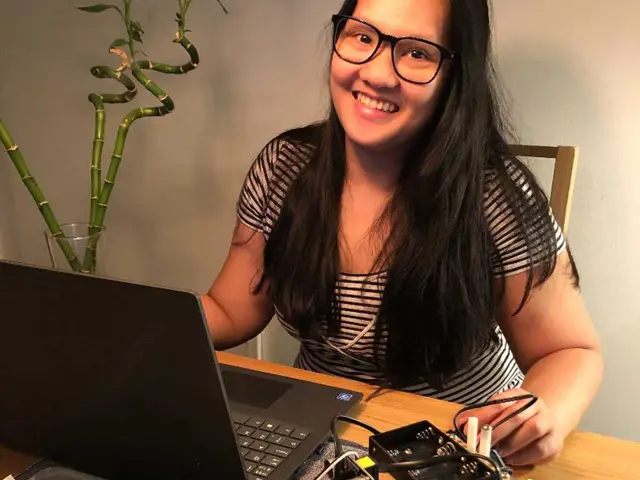 Portrett av Lucille foran en bærbar datamaskin og en minirobot