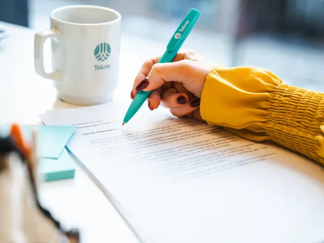 Hånd med kulepenn noterer på en utskrevet søknadstekst