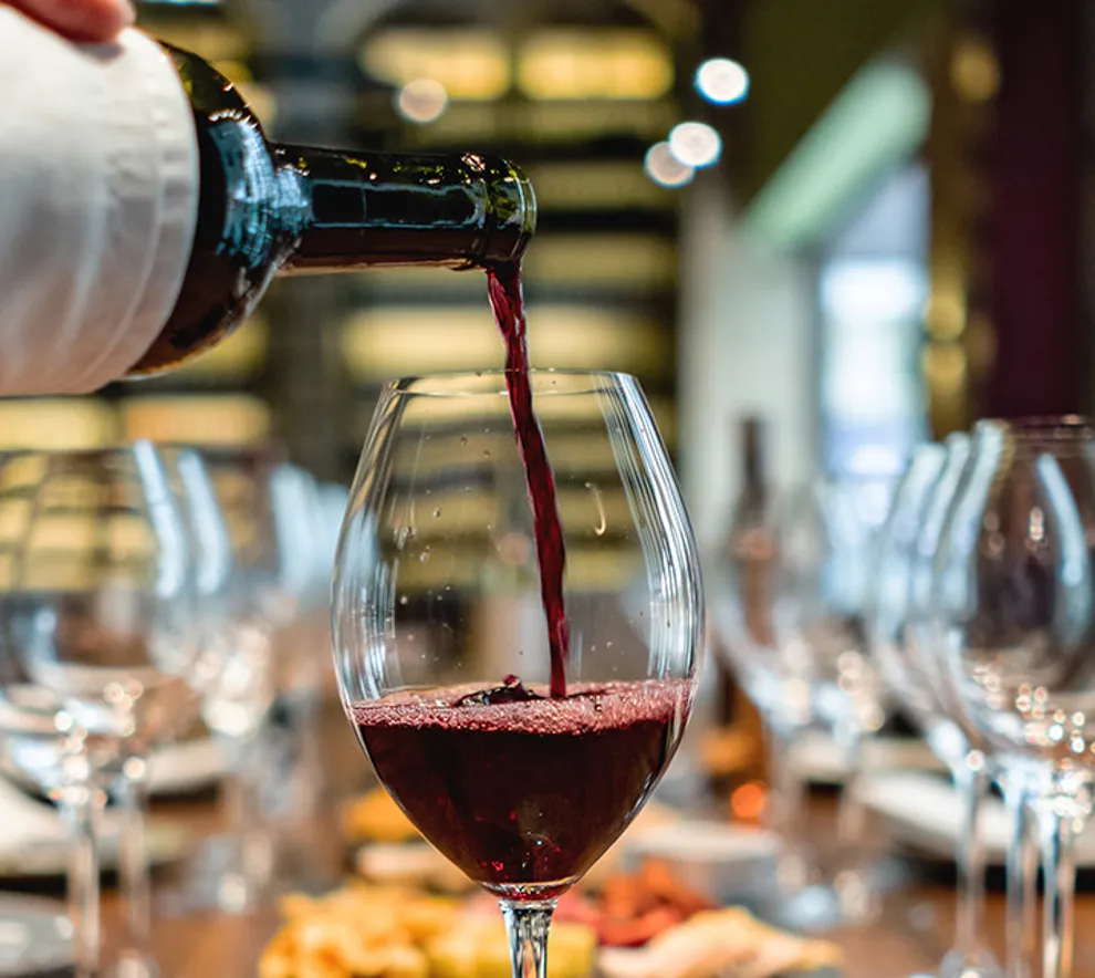 Sommelier heller rødvin i glass på restaurant