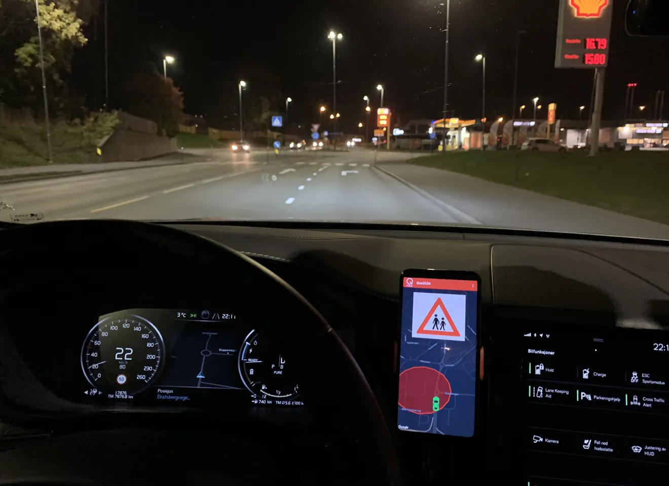 Utsikt ut av en bil om natten med en skjerm som viser veien og varsler