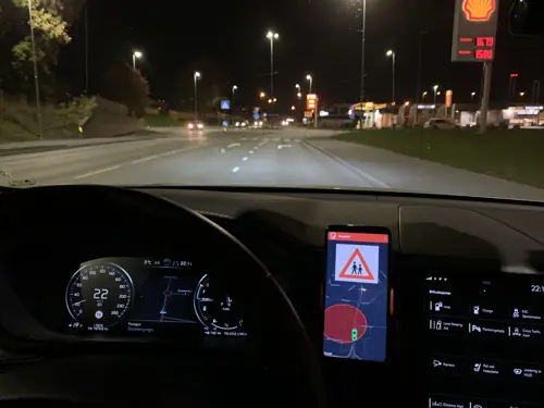 Utsikt ut av en bil om natten med en skjerm som viser veien og varsler