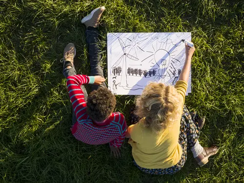To barn tegner på en gressplen