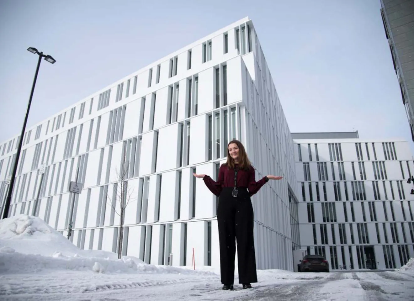 Marthe Oline Snørteland står utenfor et moderne kontorbyg i hvite stein med lange tynne vinduer