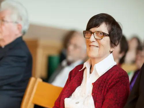 Eldre kvinne i forsamlingssal