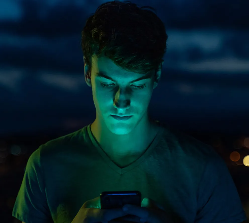 En mann som ser på telefonen utendørs i mørket