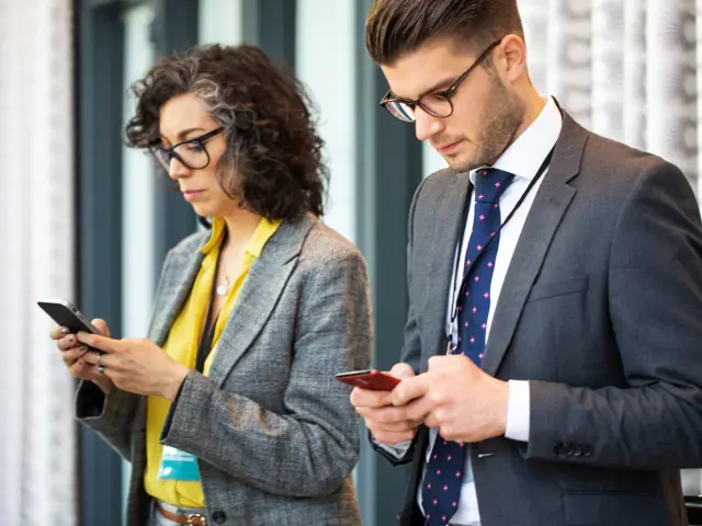 to kollegaer står og surfer på sosiale medier sammen