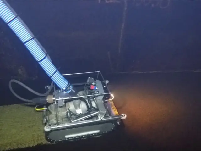 En liten robot på kjetting kjører og vasker i en mørk tunnel