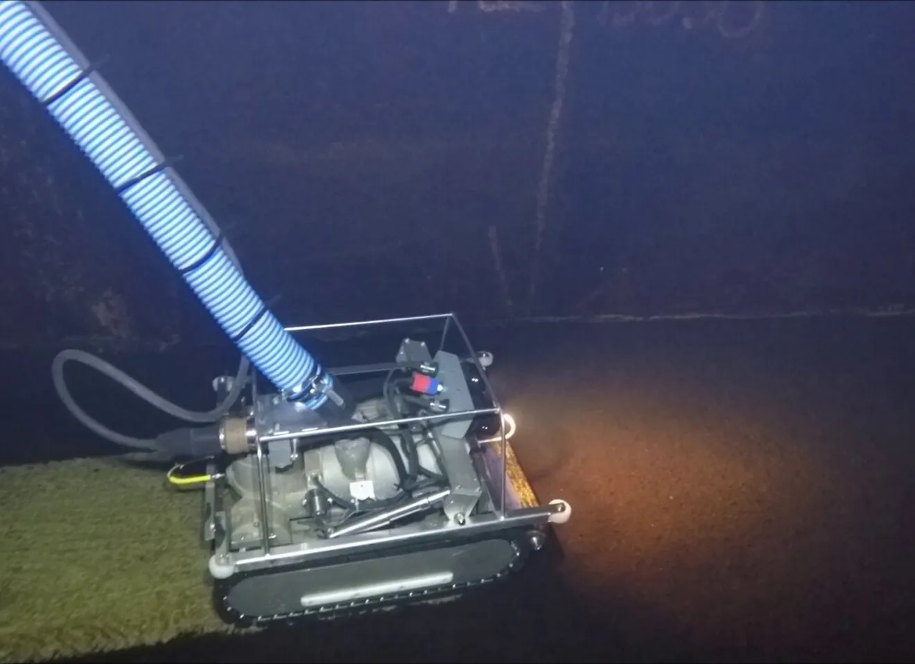 En liten robot på kjetting kjører og vasker i en mørk tunnel
