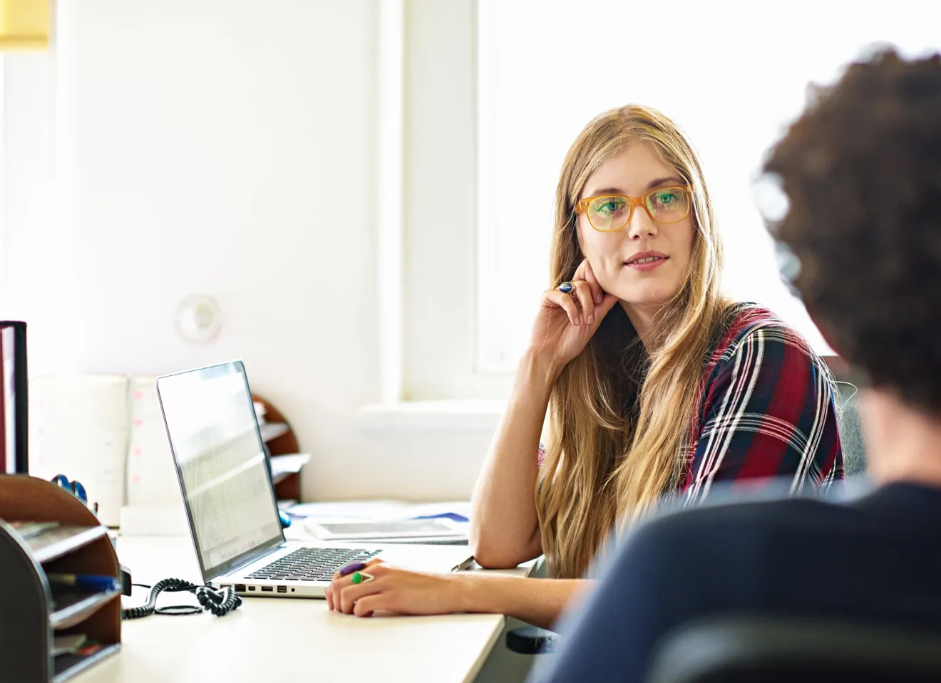 Kvinne foran en PC ser på en annen person