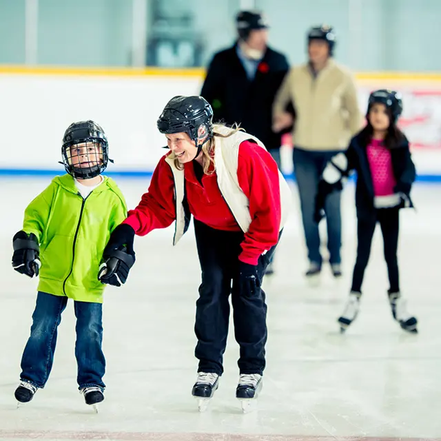 Familier står på skøyter i ishall