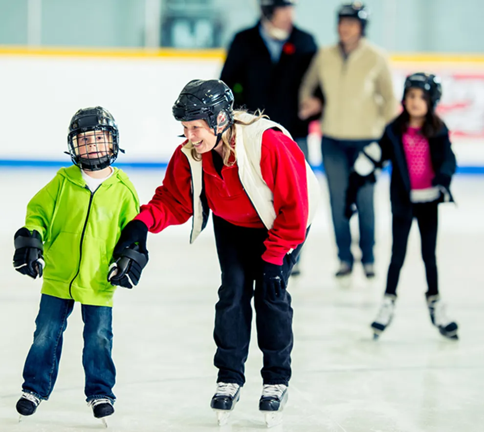 Familier står på skøyter i ishall