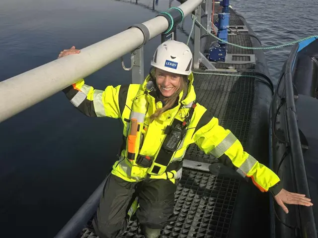 Kvinne står ved fisemerd på sjøen