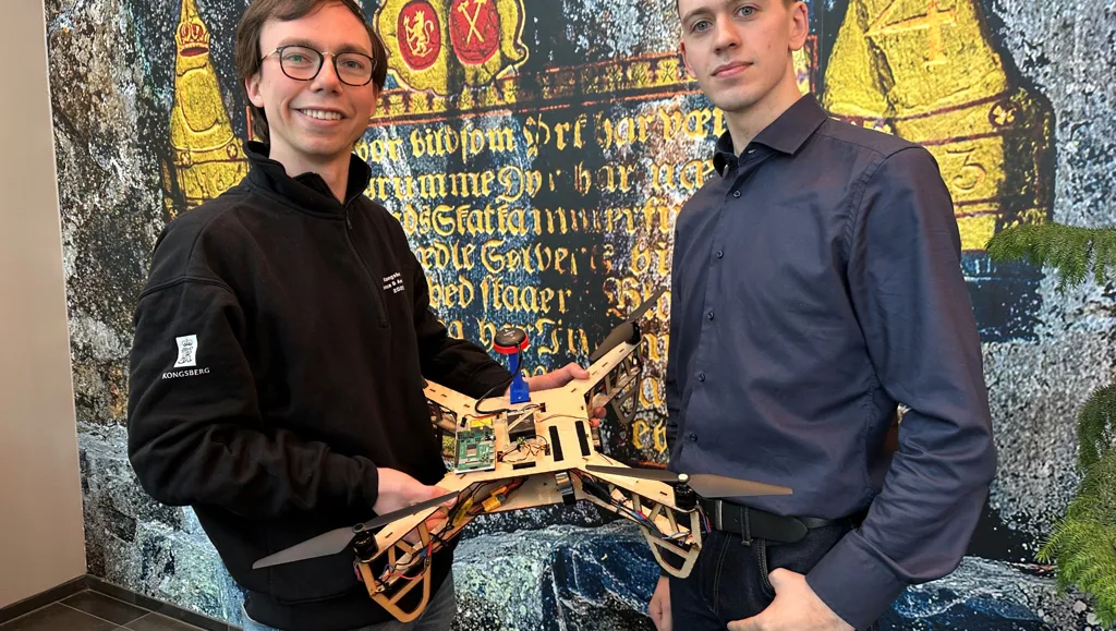 2 menn m drone foran vegg med kongesegl