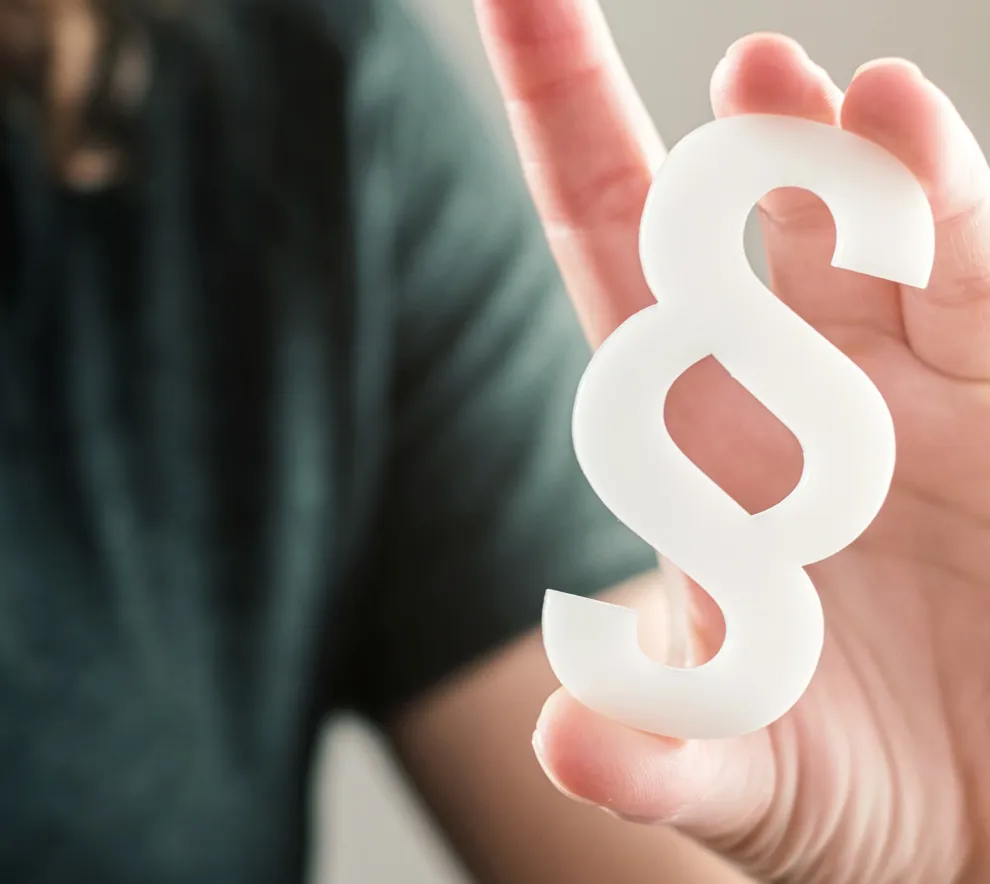 En hånd holder et paragraf-tegn