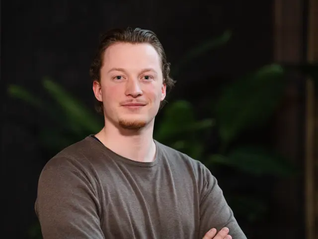 Mann med armene i kors ser inn i kamera