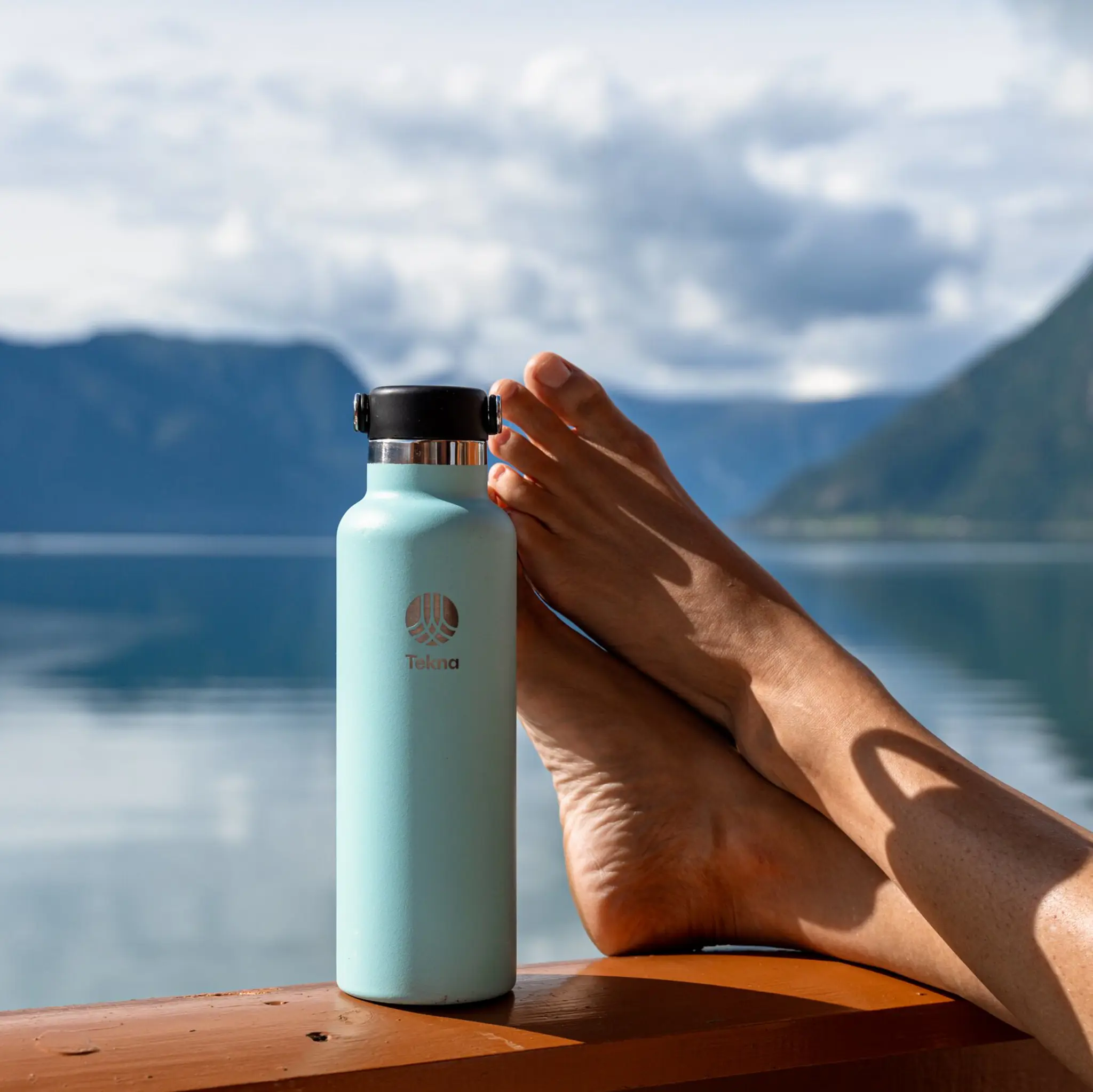 avslappede føtter ved fjorden med vannflaske