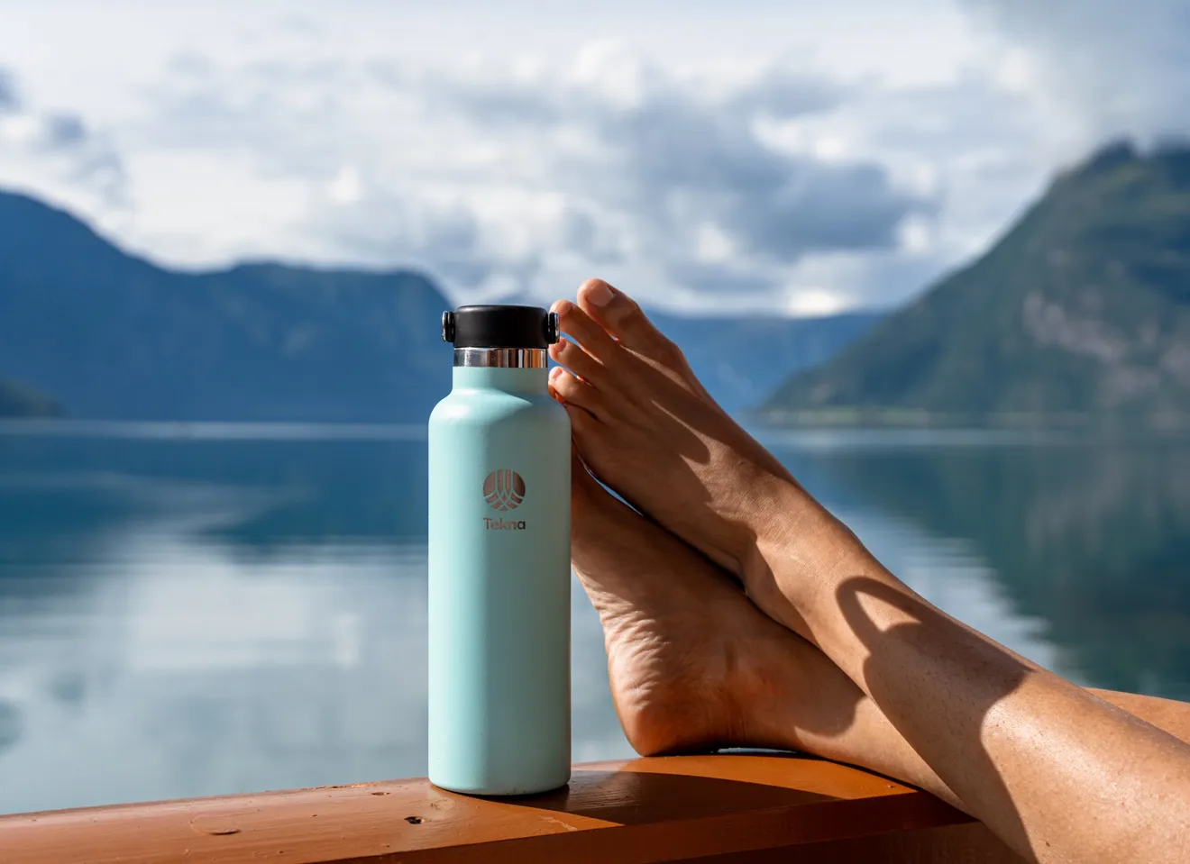 avslappede føtter ved fjorden med vannflaske