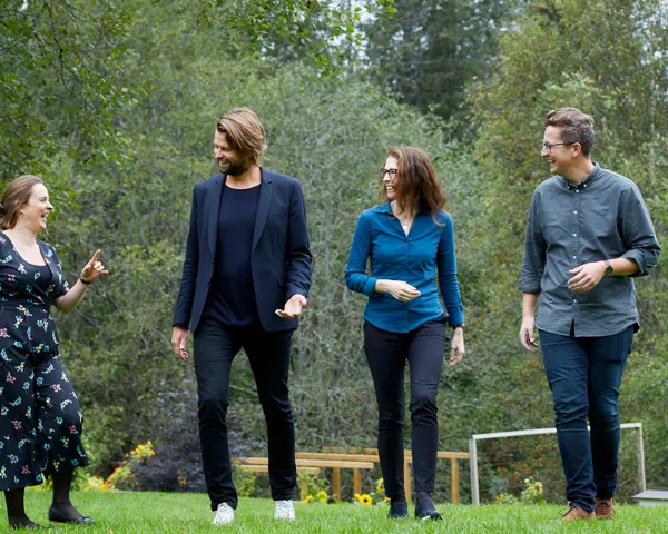 Gruppebilde av Agnethe Ellingsen, Martine Austad Langberg, Kristin Haug og Per-Magnus Moe Thompson gående på en gressplen og smiler til hverandre