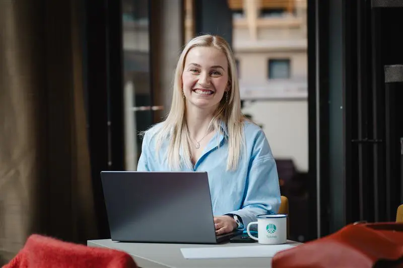 Kvinne smiler med laptop