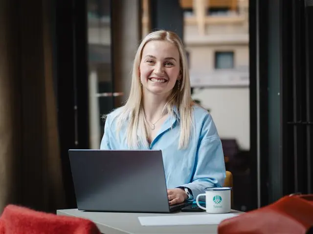 Kvinne smiler med laptop