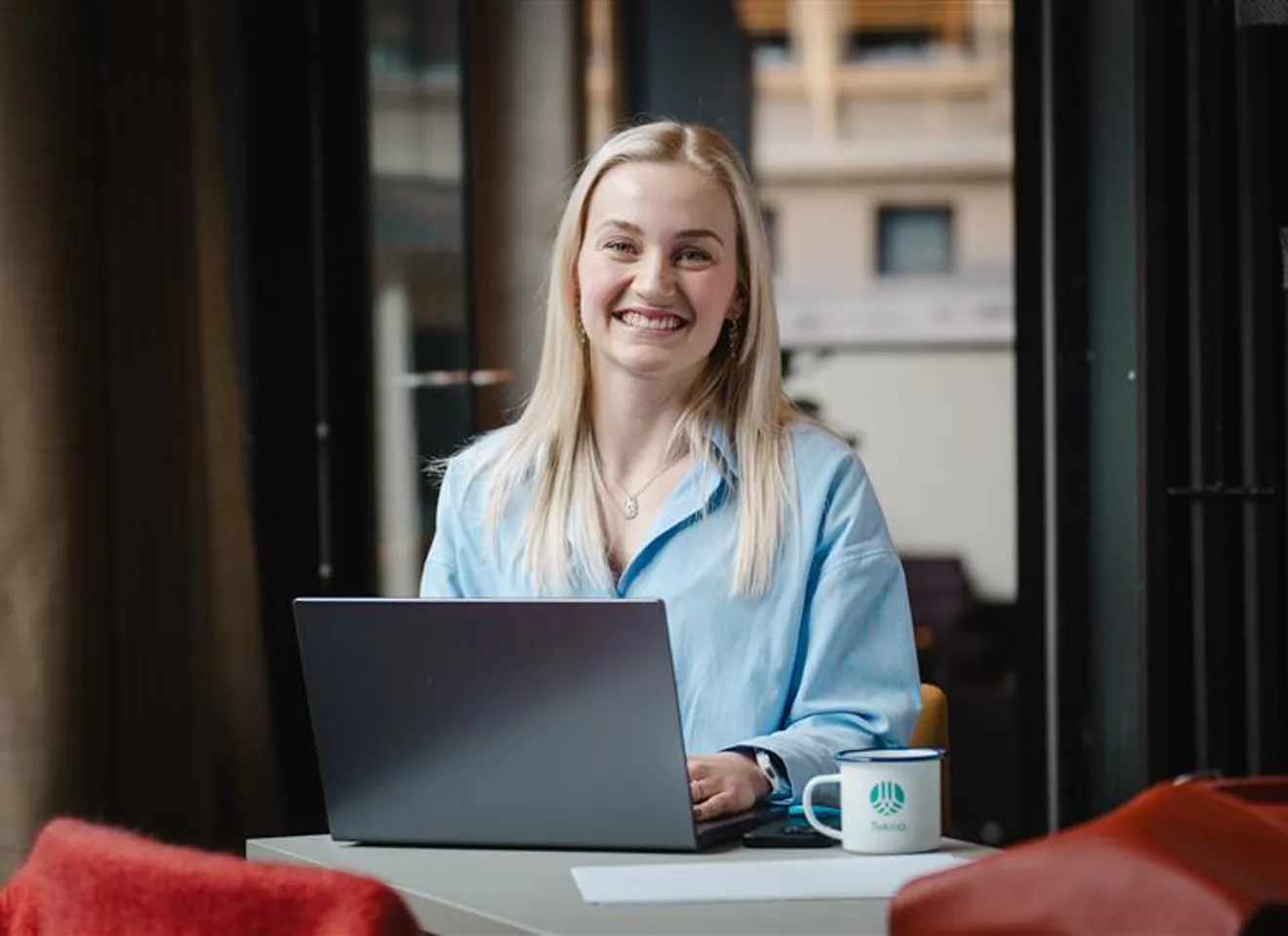 Kvinne smiler med laptop