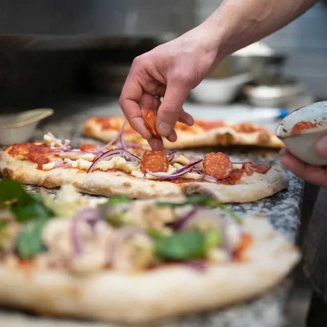 Person som lager pizza