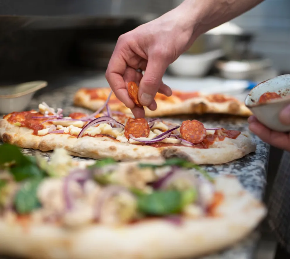 Person som lager pizza