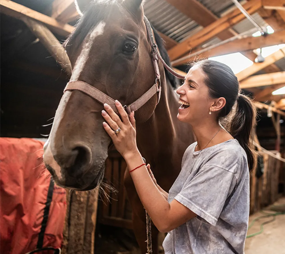Ung kvinne som klapper en hest