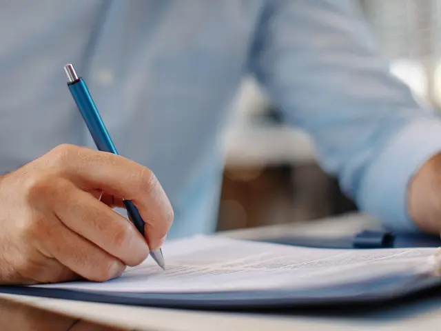 Nærbilde av en hånd med en pen som signerer en avtale