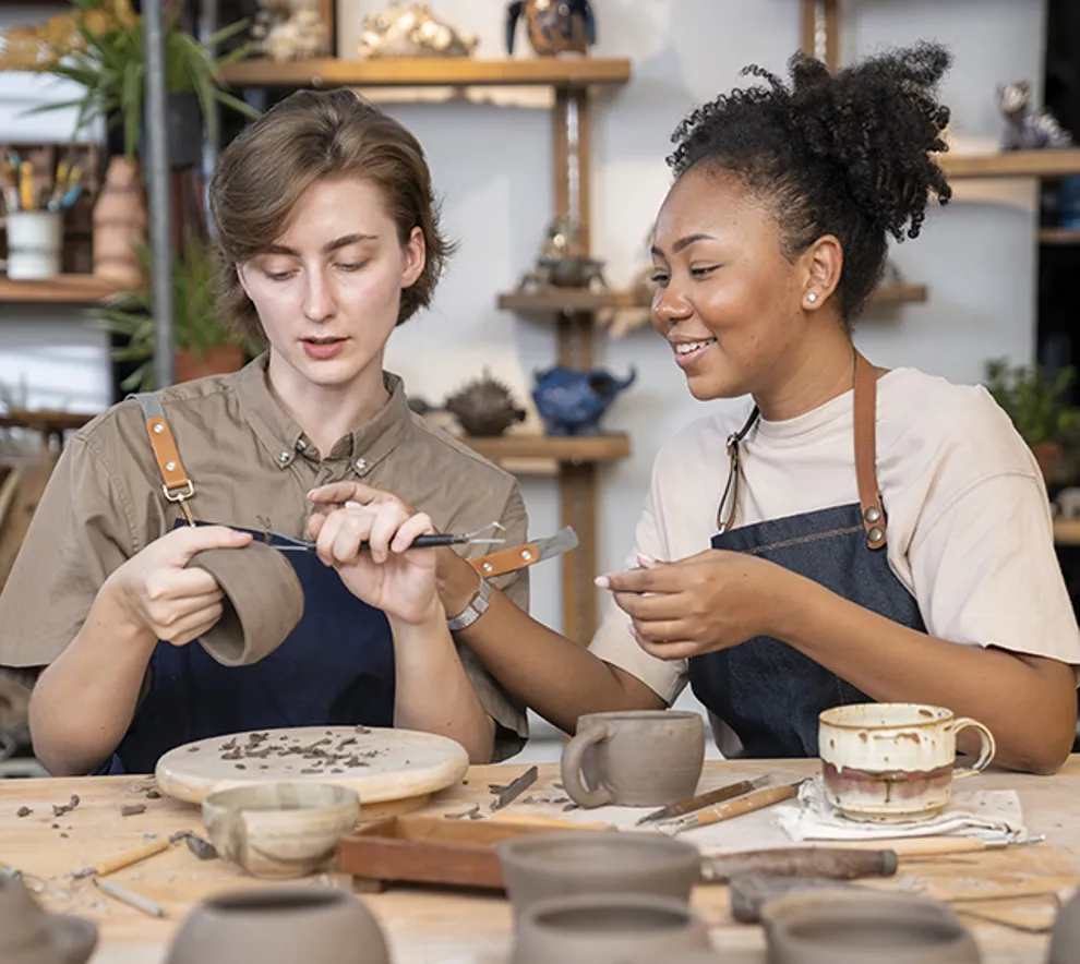 To jenter som jobber med en kopp som lages av leire