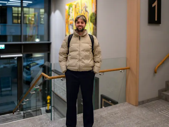 Mann i lys boblejakke ved trapp