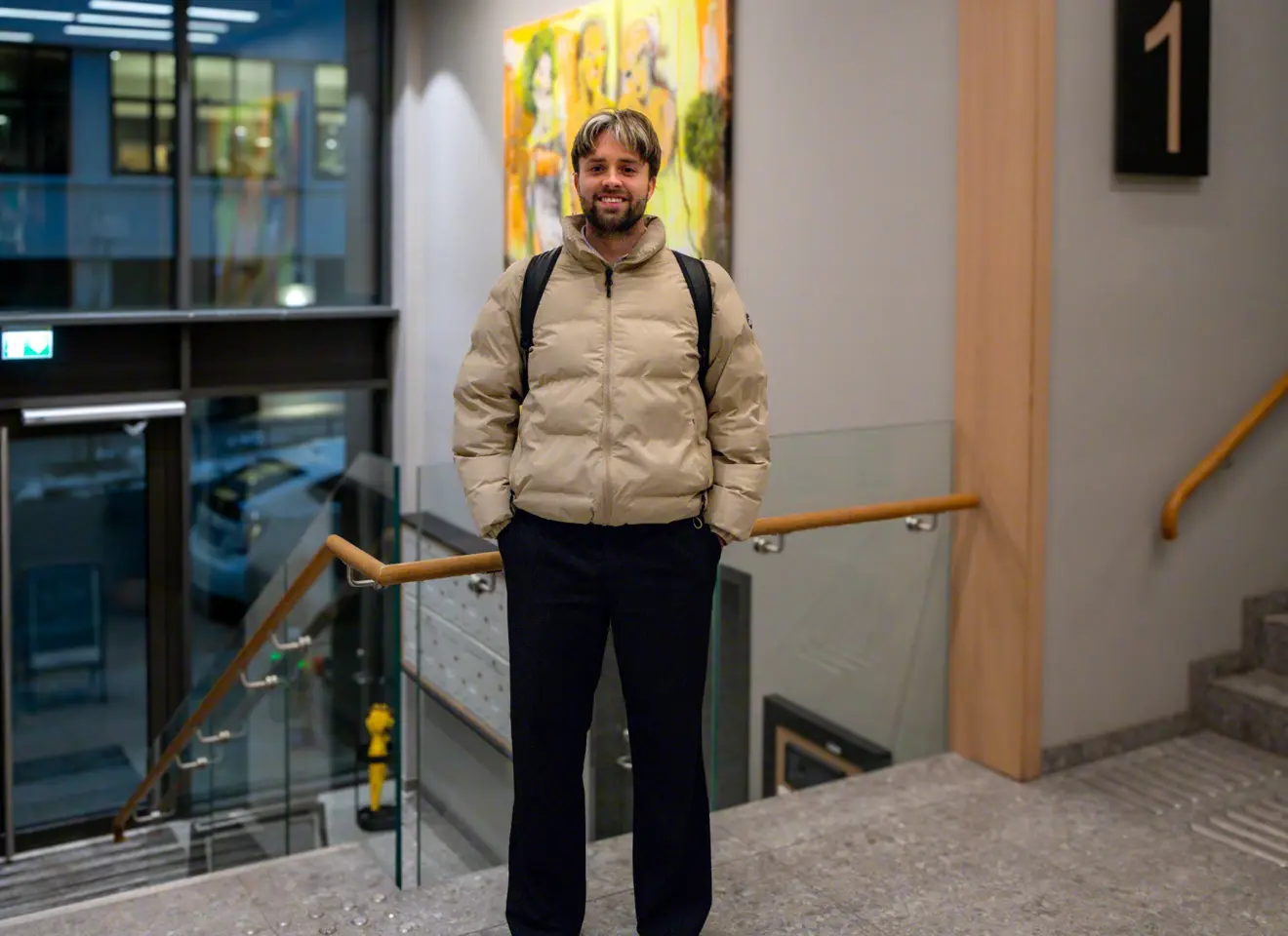 Mann i lys boblejakke ved trapp