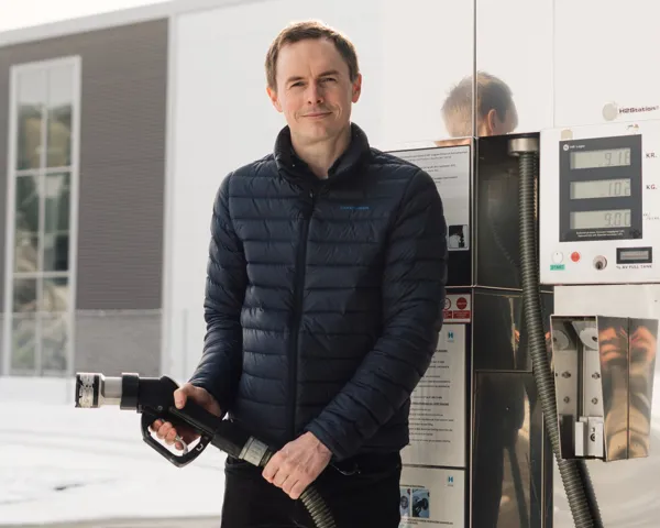 Fredrik Aarskog står på en bensinstasjon og holder slangen