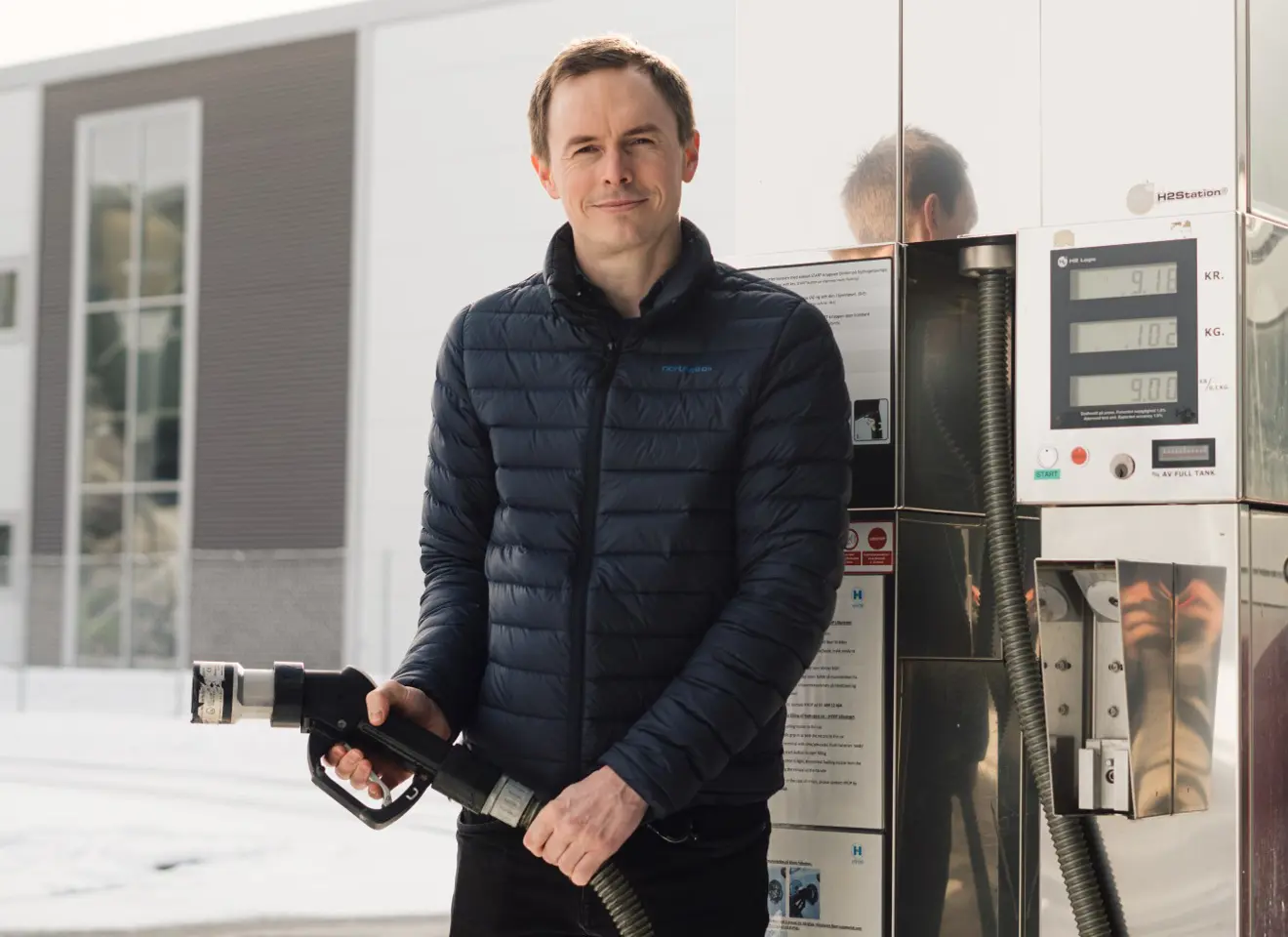Fredrik Aarskog står på en bensinstasjon og holder slangen