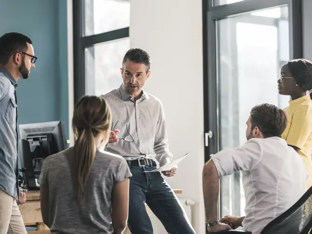 Illustrasjonsbilde av en mann som snakker med 3-4 ansatte