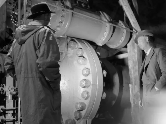 Gammel sorthvit bilde av to ingeniører som ser på et stor rør i en mørk tunnel