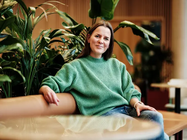 Kvinne i grønn genser i sofa med planter rundt