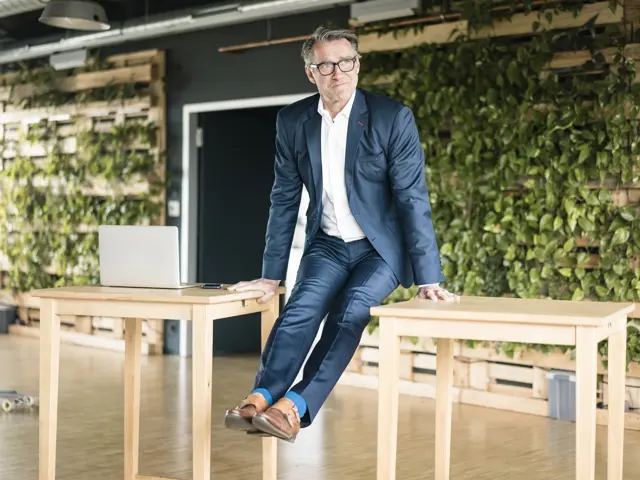 Illustrasjonsbilde av en mann i dress som gjør pushups mellom to kontorpult