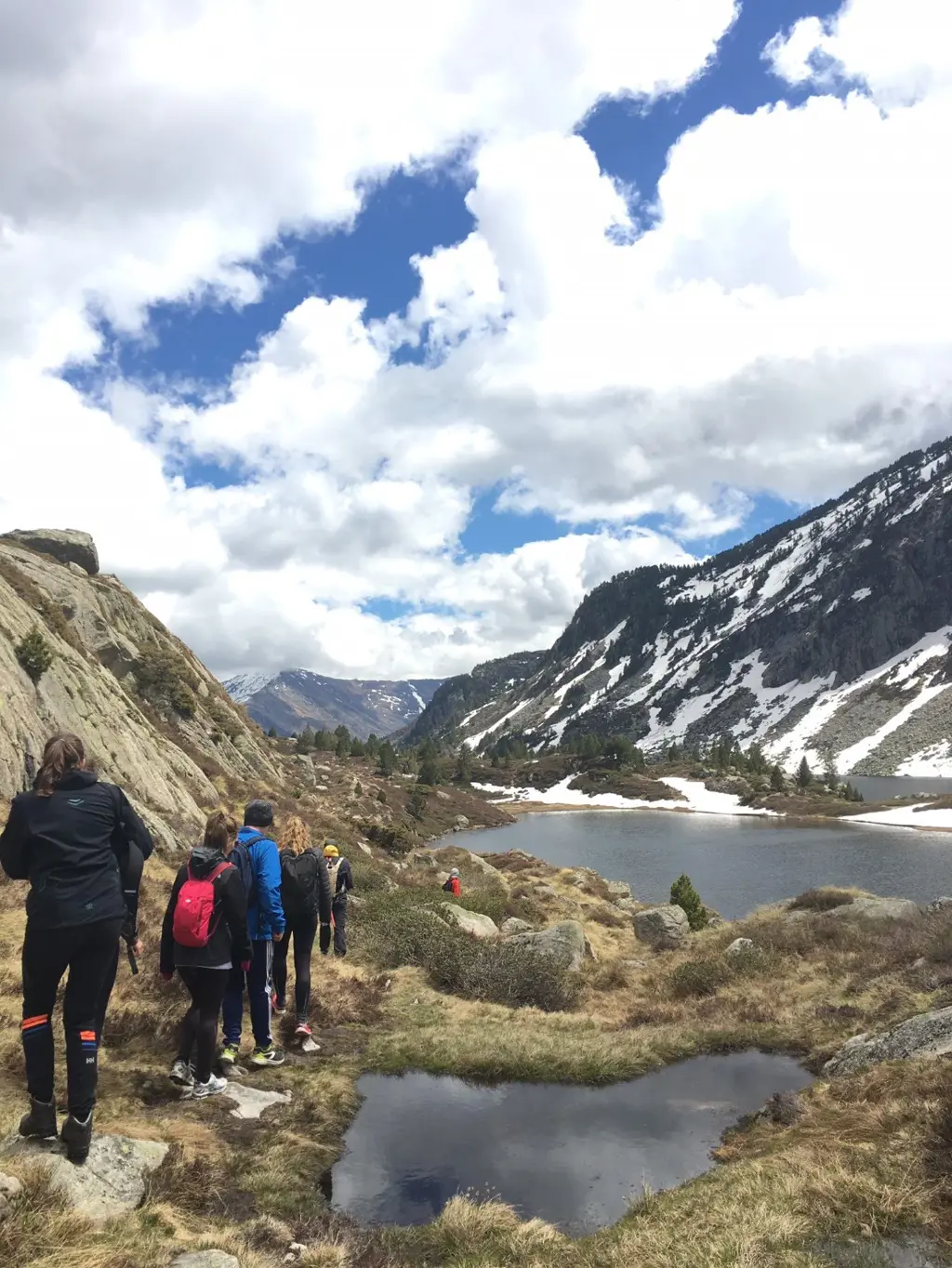 En gruppe mennesker på tur ved siden av en innsjø mellom to fjell